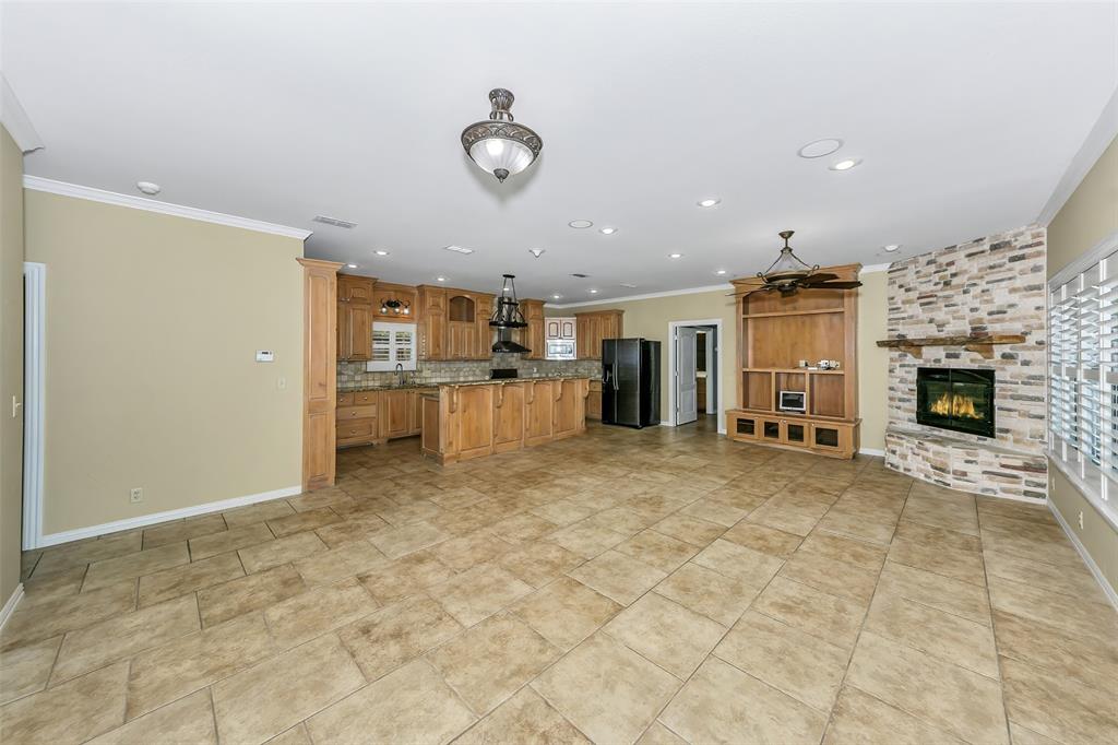 566 Selma Park Road Bowie, TX 76230 - Photo 8 of 40 Expansive open-concept living area featuring large format tile flooring, a built-in media center with ceiling fan, and a stone-clad fireplace