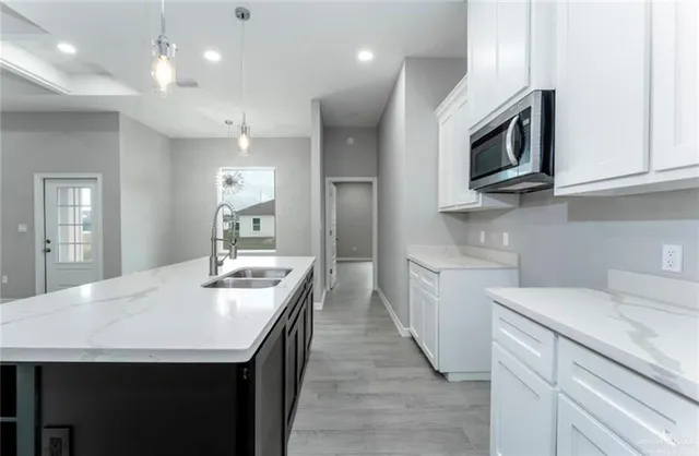 a kitchen with stainless steel appliances granite countertop a sink a microwave oven a refrigerator and white cabinets