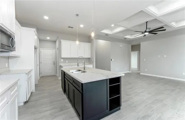 a kitchen with a sink a counter top space stainless steel appliances and a ceiling fan