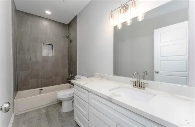 a bathroom with a granite countertop sink a toilet and bathtub