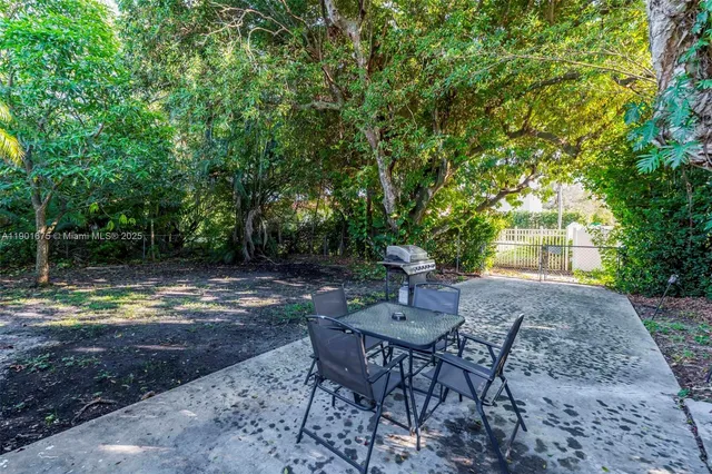 a view of a backyard with table and chairs and a tree