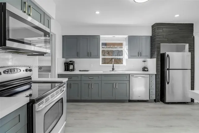 a kitchen with a sink cabinets stainless steel appliances and a window