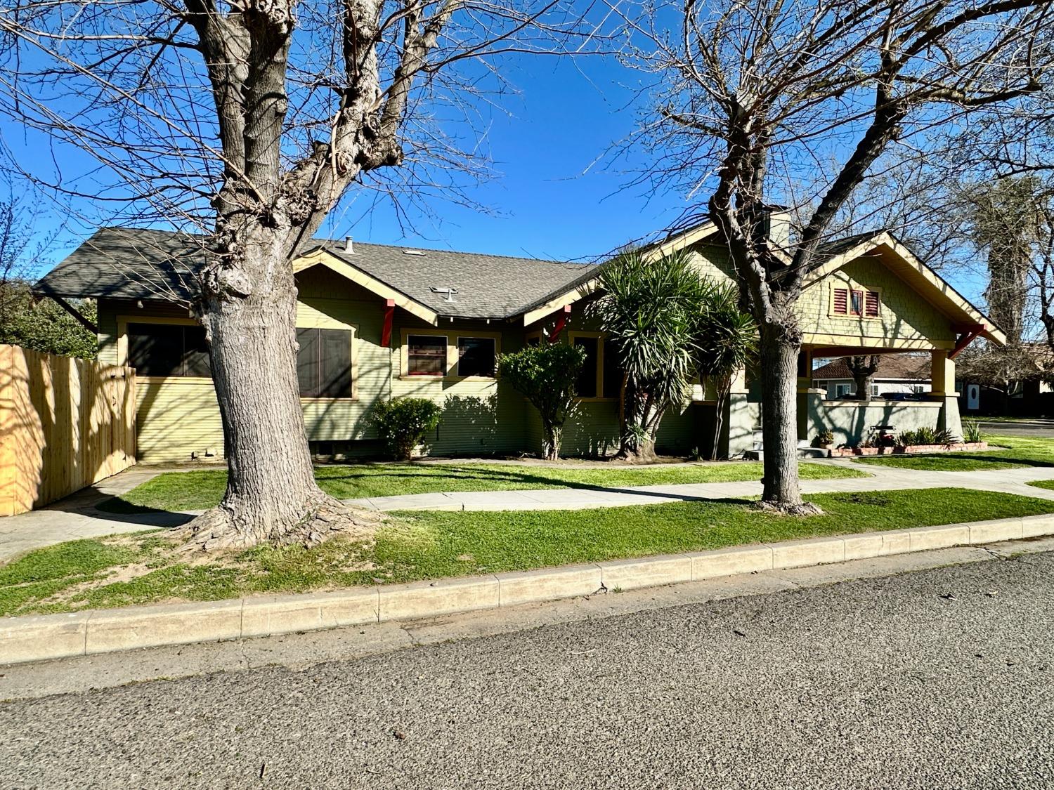 1059 Q Street Newman, CA 95360 - Photo 3 of 29 a yellow house with trees in front of it