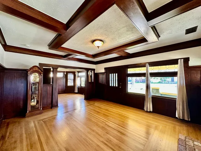 a view of an empty room with wooden floor and windows