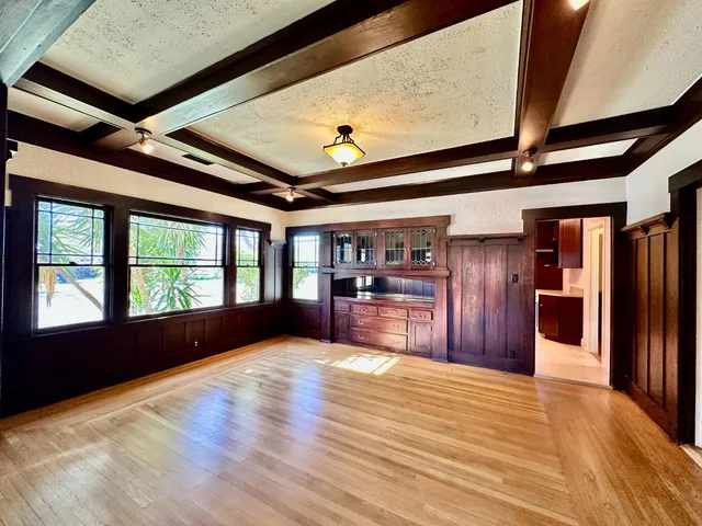 a view of an empty room with kitchen natural and wooden floor
