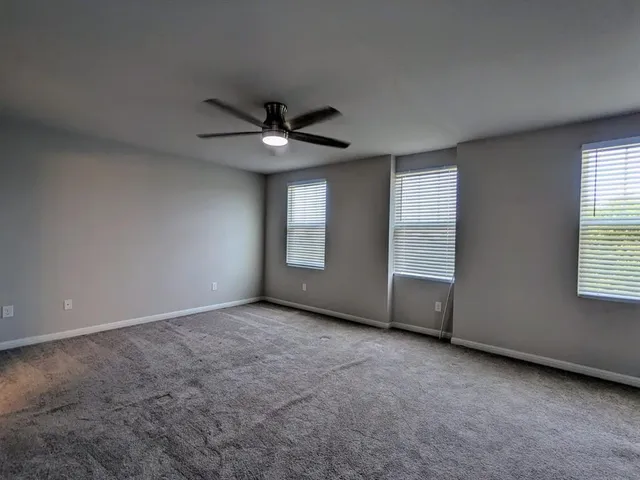 an empty room with windows and ceiling fan