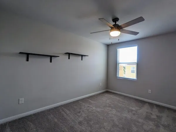 an empty room with a window and a fan