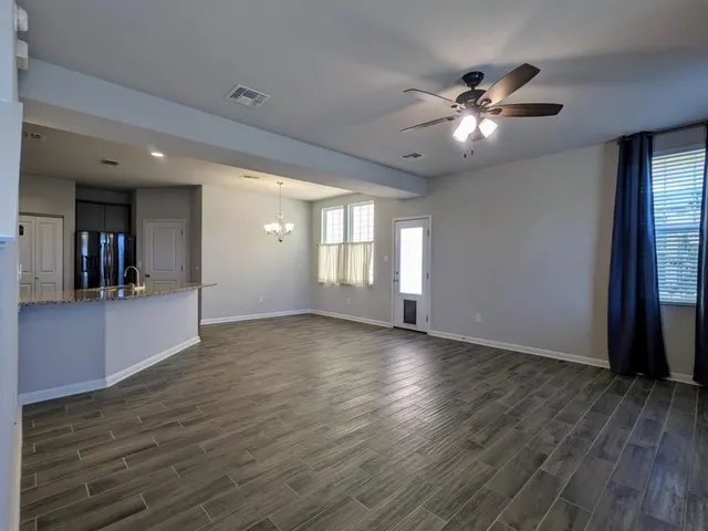 a view of an empty room with window and wooden floor