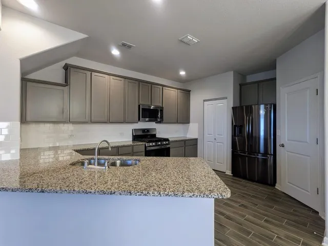 a kitchen with stainless steel appliances granite countertop a sink refrigerator and microwave