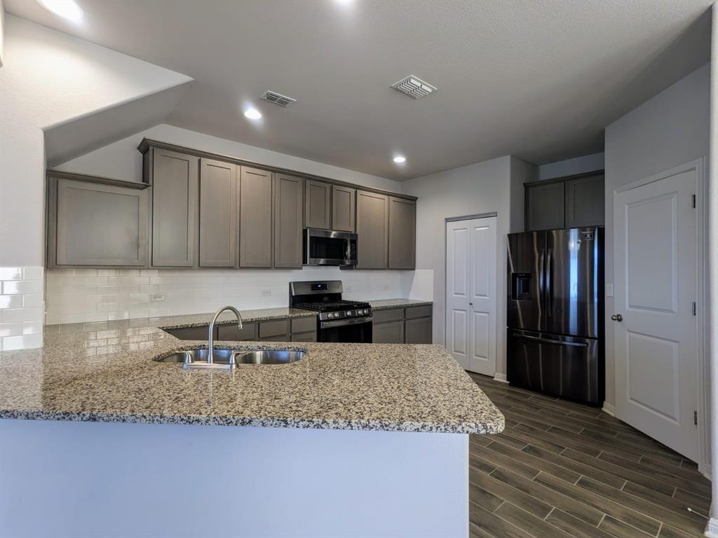 196 Martha Lane Kyle, TX 78640 - Photo 7 of 30 a kitchen with stainless steel appliances granite countertop a sink refrigerator and microwave