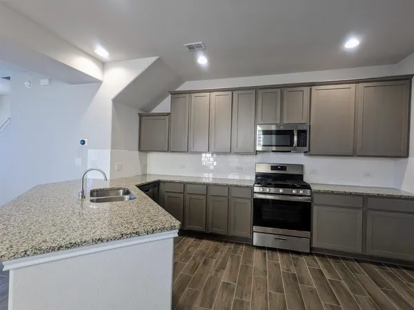 a kitchen with stainless steel appliances granite countertop a sink stove microwave and cabinets