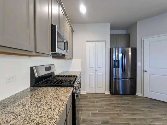 a kitchen with stainless steel appliances granite countertop a refrigerator and a stove top oven