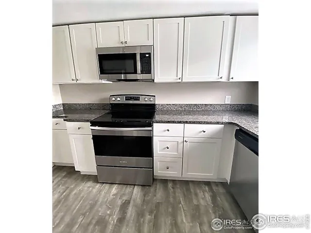 a kitchen with granite countertop white cabinets and appliances