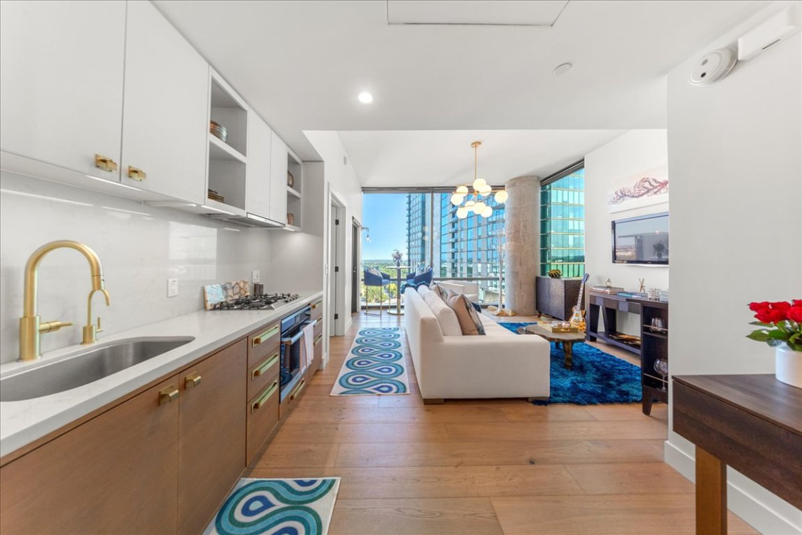 70 Rainey Street, Unit 1503 Austin, TX 78701 - Photo 2 of 30 Kitchen featuring expansive windows, light wood-style flooring, open shelves, a chandelier, and wall oven