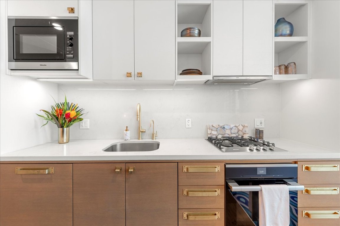 70 Rainey Street, Unit 1503 Austin, TX 78701 - Photo 7 of 30 Kitchen featuring black appliances, open shelves, decorative backsplash, and light stone countertops