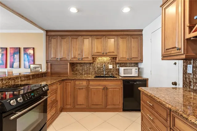 a kitchen with stainless steel appliances granite countertop a stove a sink and a microwave