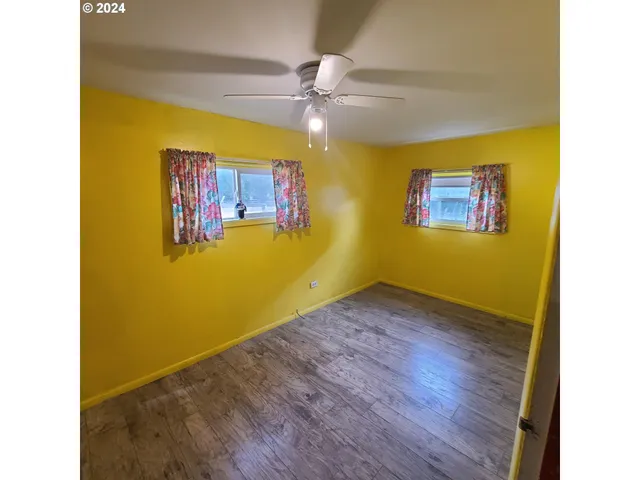 a view of a room with wooden floor and a ceiling fan