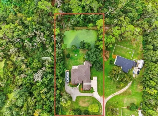 an aerial view of residential house with outdoor space and trees all around