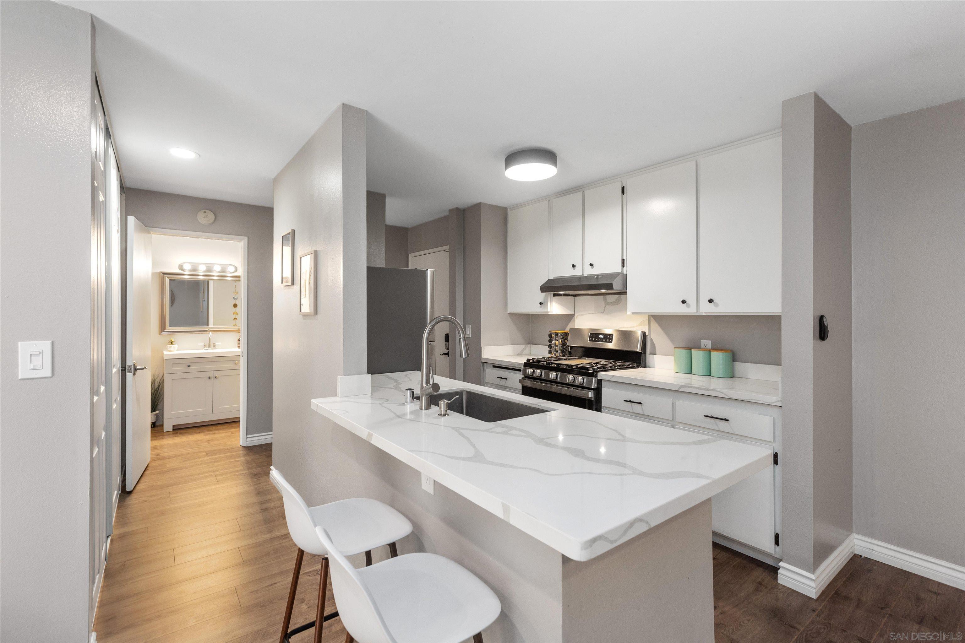 a kitchen with a sink a stove a refrigerator and white cabinets