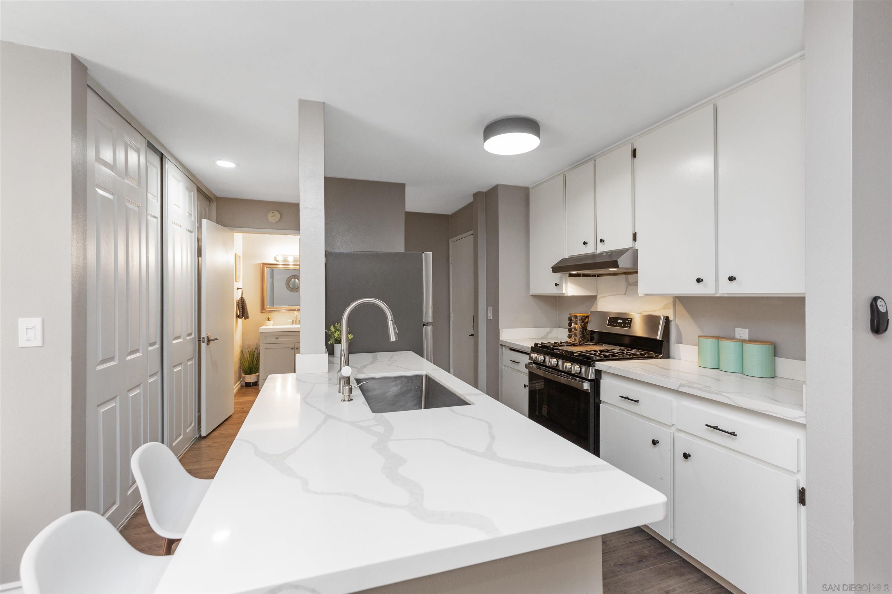 1621 Unit E 217, Unit E217 San Diego, CA 92108 - Photo 9 of 45 a kitchen with stainless steel appliances a sink a stove a refrigerator cabinets and a dining table