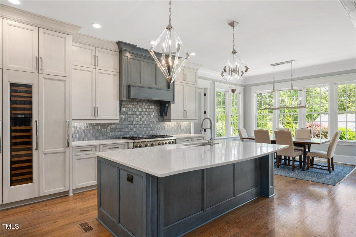 6502 New Market Way Raleigh, NC 27615 - Photo 13 of 54 a kitchen with kitchen island granite countertop a stove a sink a dining table and chairs with wooden floor