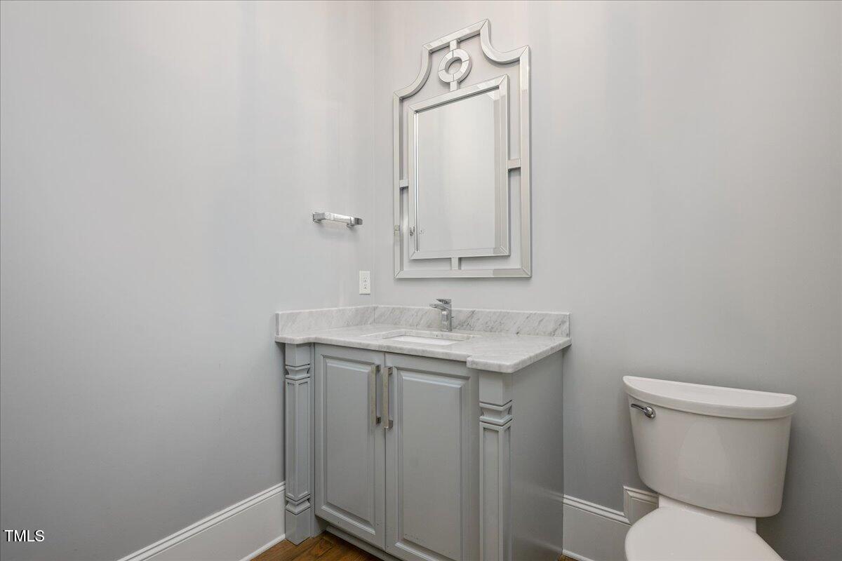 6502 New Market Way Raleigh, NC 27615 - Photo 21 of 54 a bathroom with a granite countertop toilet a sink and a mirror
