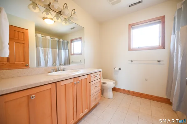 a bathroom with a granite countertop sink a toilet and a mirror