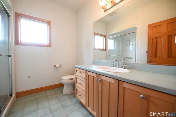 a bathroom with a granite countertop sink a toilet and a mirror