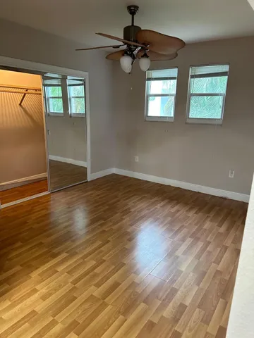 a view of an empty room with wooden floor and a window