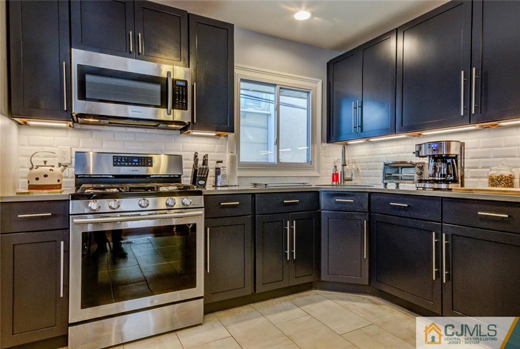 106 Rector Street Perth Amboy, NJ 08861 - Photo 2 of 20 a kitchen with granite countertop wooden cabinets stainless steel appliances and a window