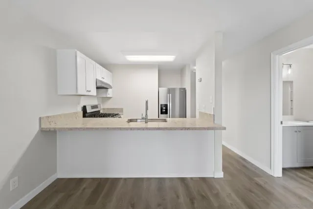 a large white kitchen with wooden floor