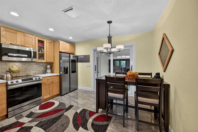 a kitchen with stainless steel appliances granite countertop a stove a sink dishwasher a dining table and chairs with wooden floor