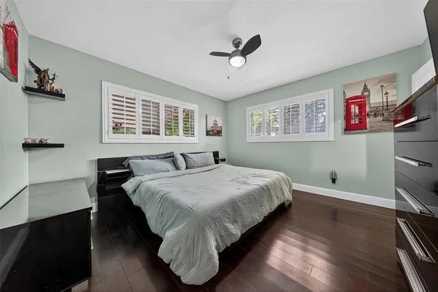 a bedroom with a bed and dresser with wooden floor