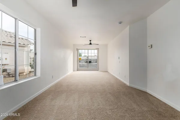 an empty room with a ceiling fan and hallway