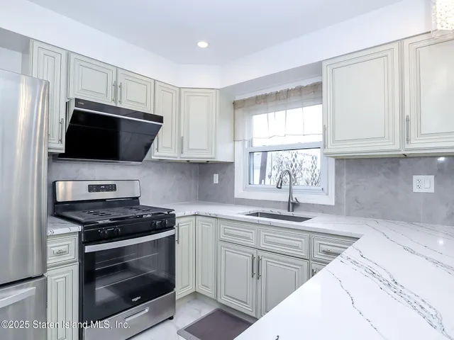 a kitchen with stainless steel appliances granite countertop a sink dishwasher a stove and a microwave oven with cabinets