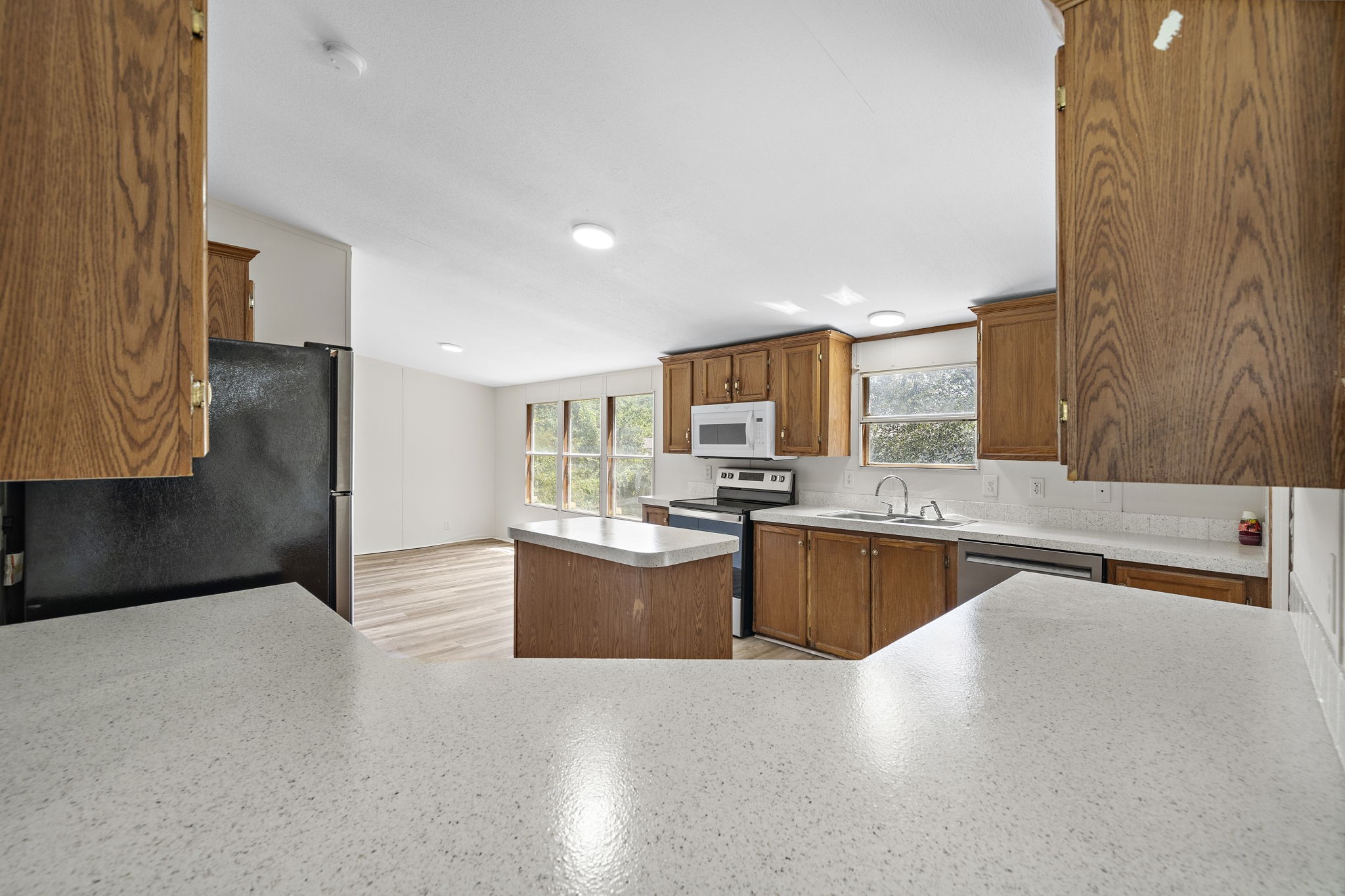 16482 Pisces Road Conroe, TX 77306 - Photo 12 of 35 a kitchen with stainless steel appliances kitchen island granite countertop a refrigerator a sink dishwasher a oven with white cabinets and wooden floor