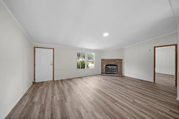 an empty room with wooden floor fireplace and windows