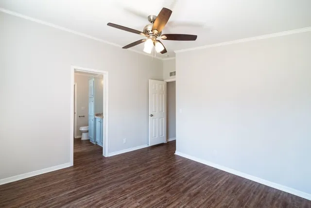 a view of an empty room with wooden floor and a ceiling fan