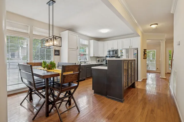 a kitchen with stainless steel appliances a dining table chairs a refrigerator and cabinets