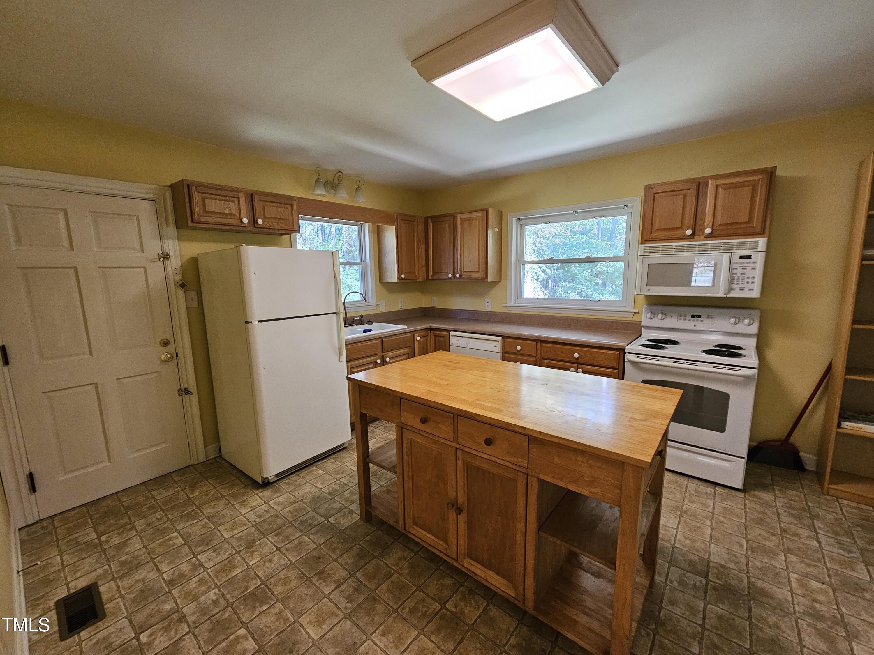 8178 Highway 751 Durham, NC 27713 - Photo 12 of 20 a kitchen with wooden cabinets a sink a stove a refrigerator and a window