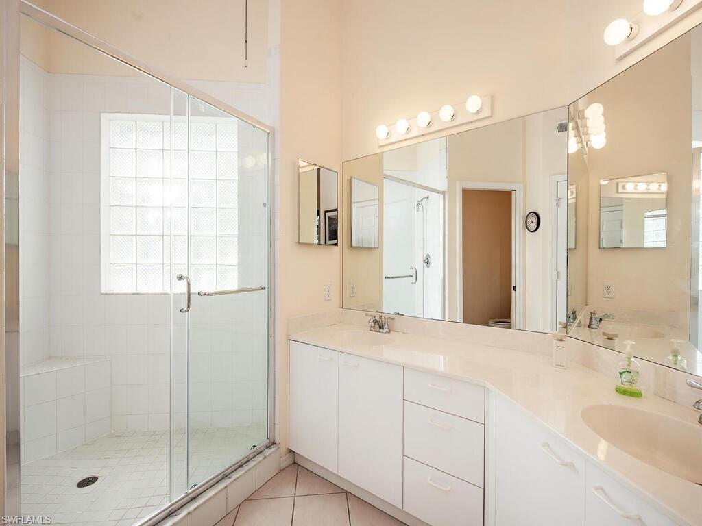 65 Silver Oaks Circle, Unit 11202 Naples, FL 34119 - Photo 12 of 12 a bathroom with a shower sink and mirror