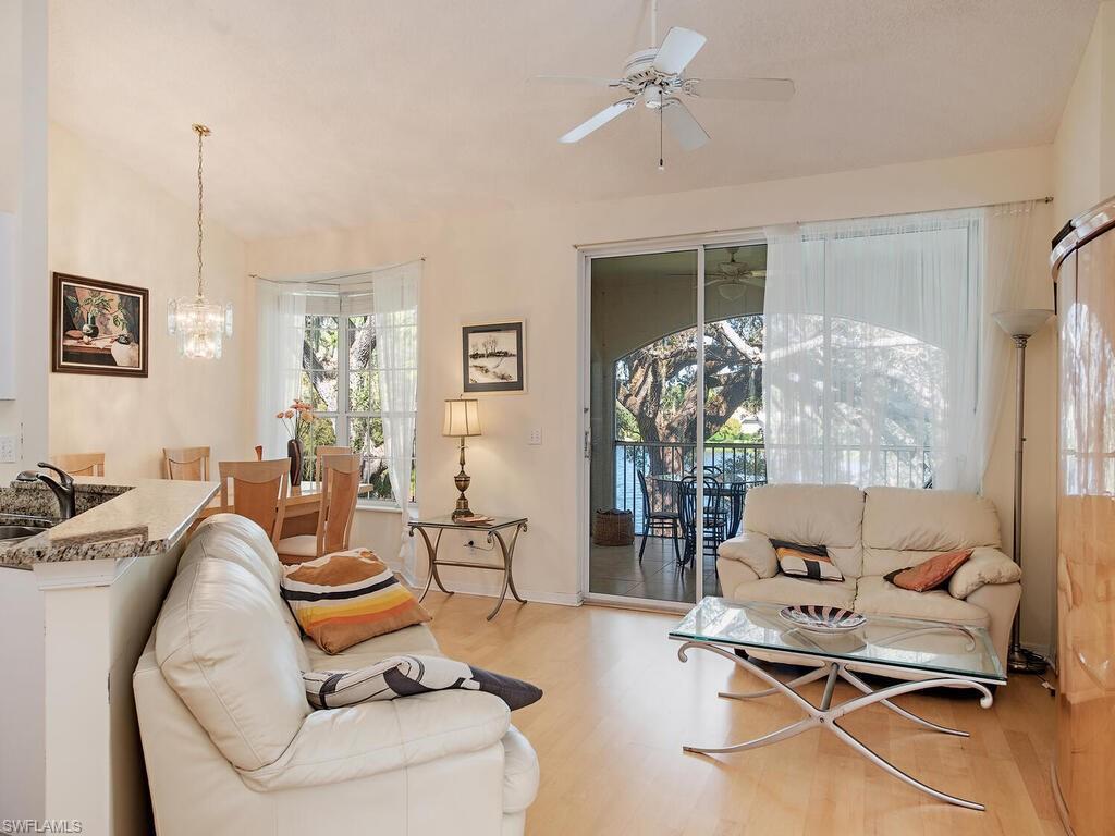 65 Silver Oaks Circle, Unit 11202 Naples, FL 34119 - Photo 5 of 12 a living room with furniture a chandelier and a floor to ceiling window