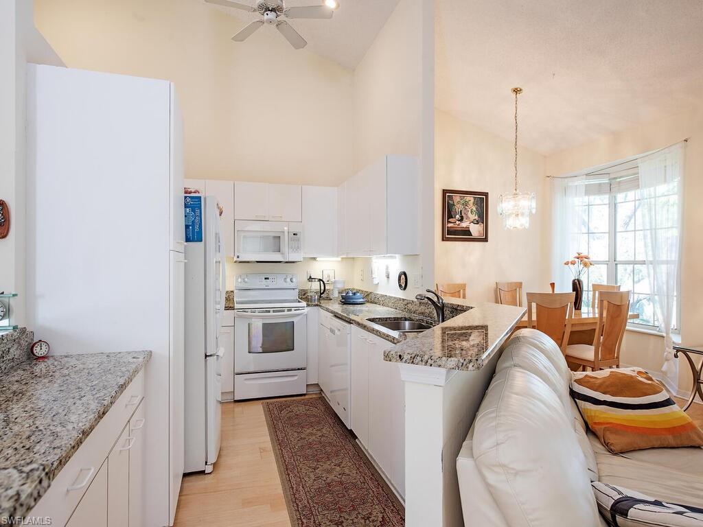 65 Silver Oaks Circle, Unit 11202 Naples, FL 34119 - Photo 7 of 12 a kitchen with stainless steel appliances granite countertop a sink stove and refrigerator