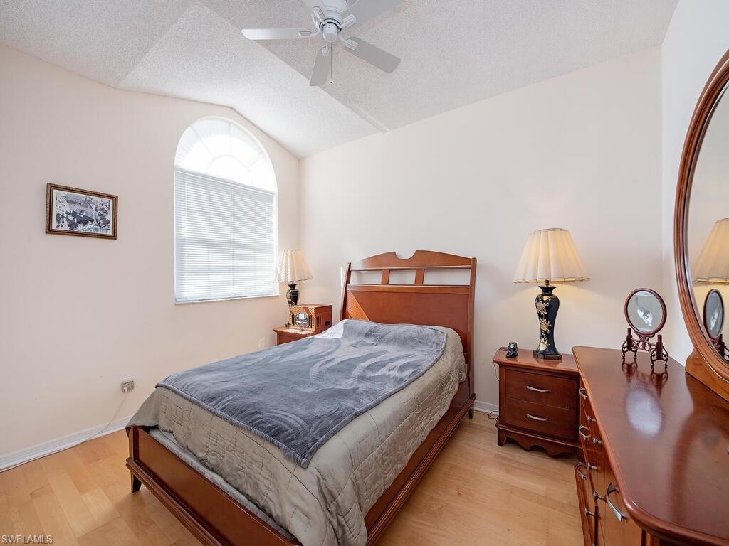 65 Silver Oaks Circle, Unit 11202 Naples, FL 34119 - Photo 8 of 12 a bedroom with a bed and wooden floor