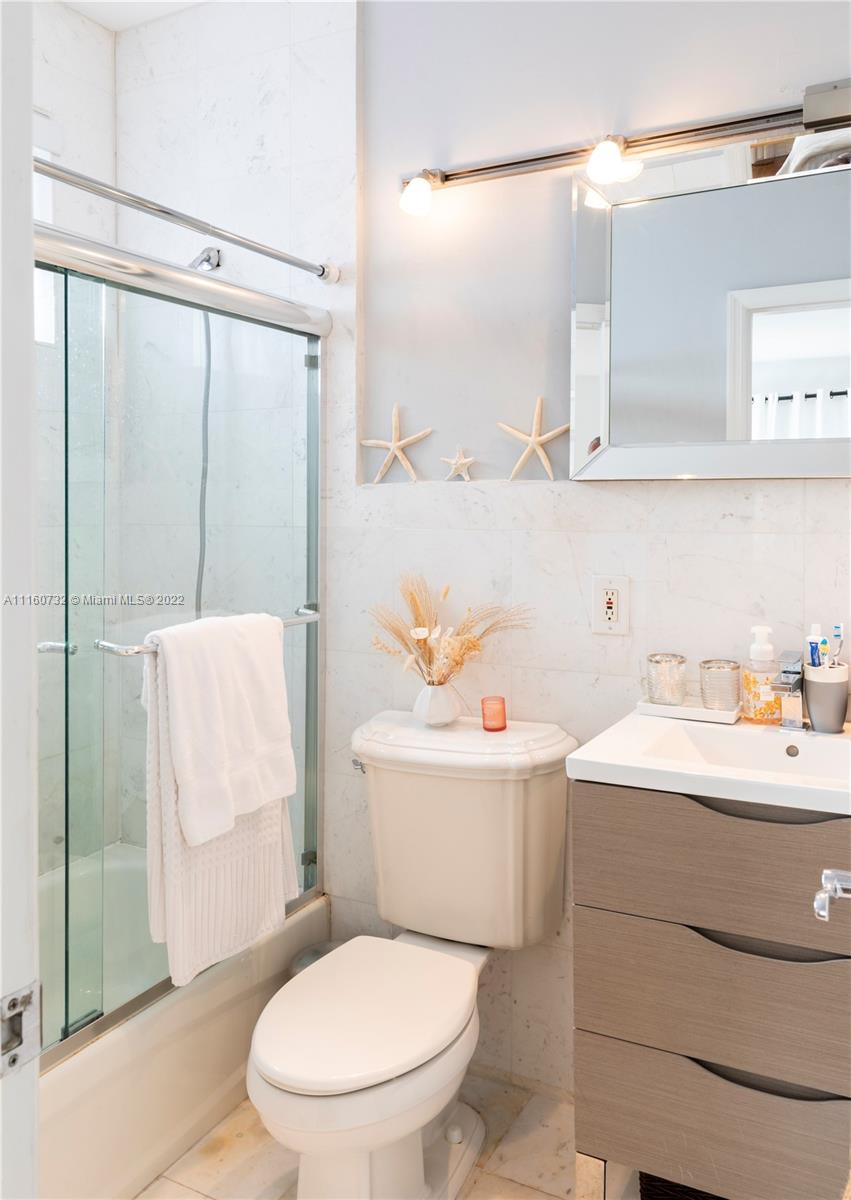 4216 Alton Road Miami Beach, FL 33140 - Photo 11 of 27 a bathroom with a sink a toilet a mirror and shower