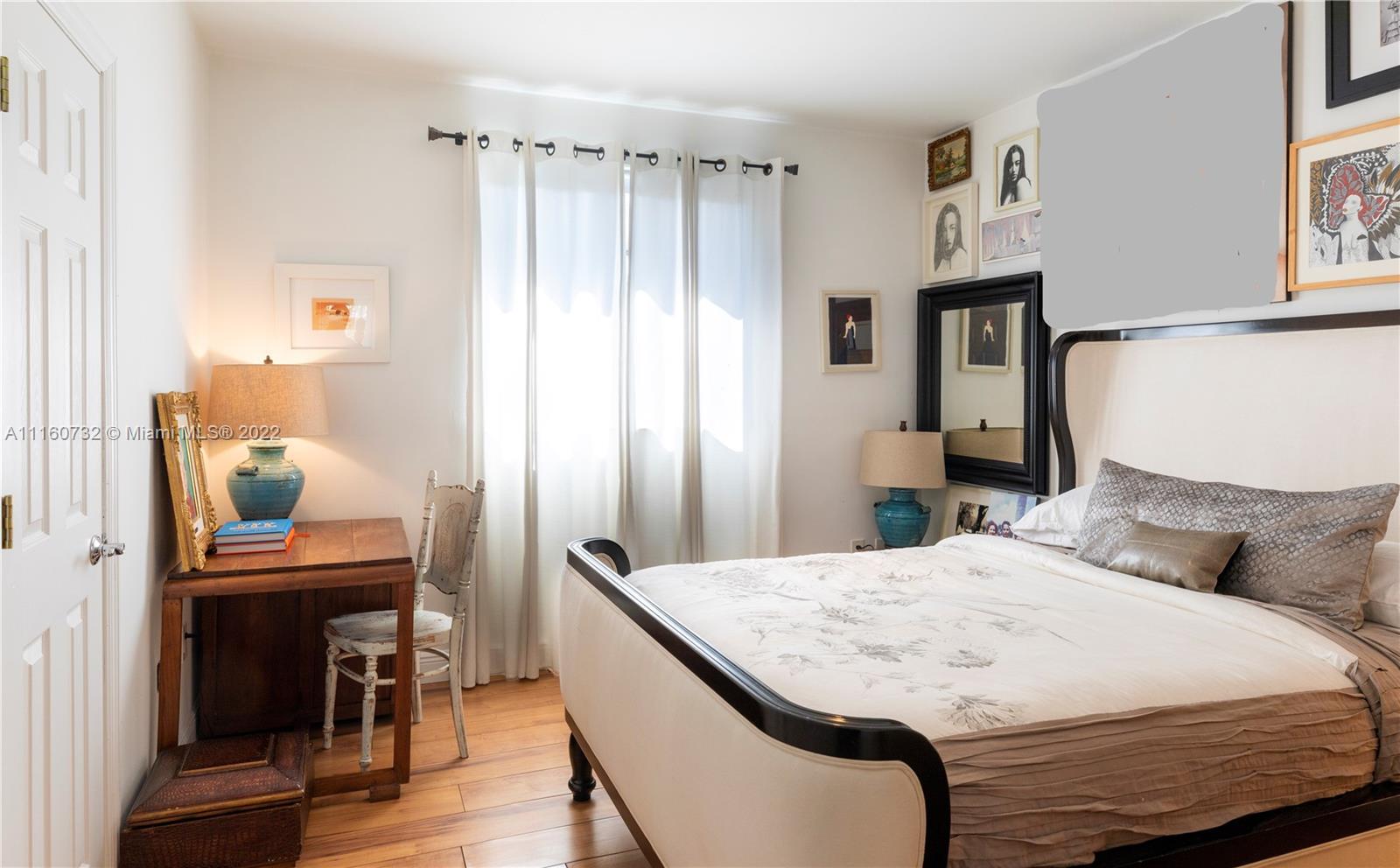 4216 Alton Road Miami Beach, FL 33140 - Photo 15 of 27 a bedroom with a bed a table and painting on the wall