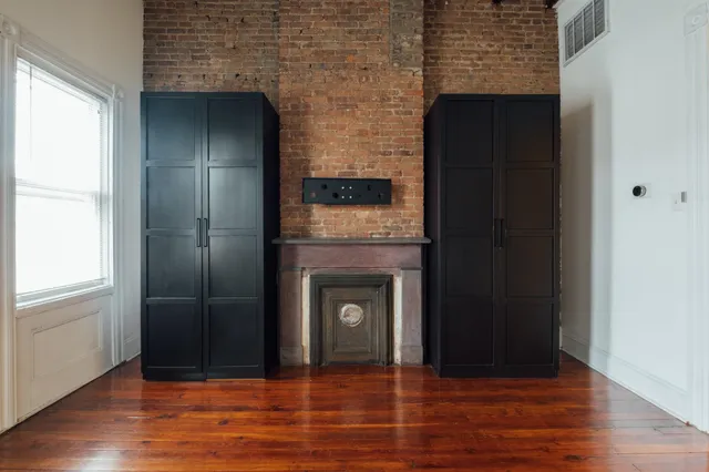 a view of an empty room with wooden floor and a fireplace