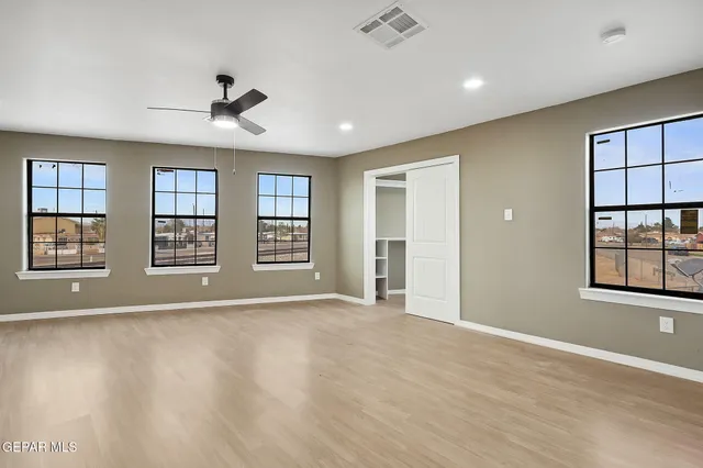 a view of an empty room with a window and wooden floor