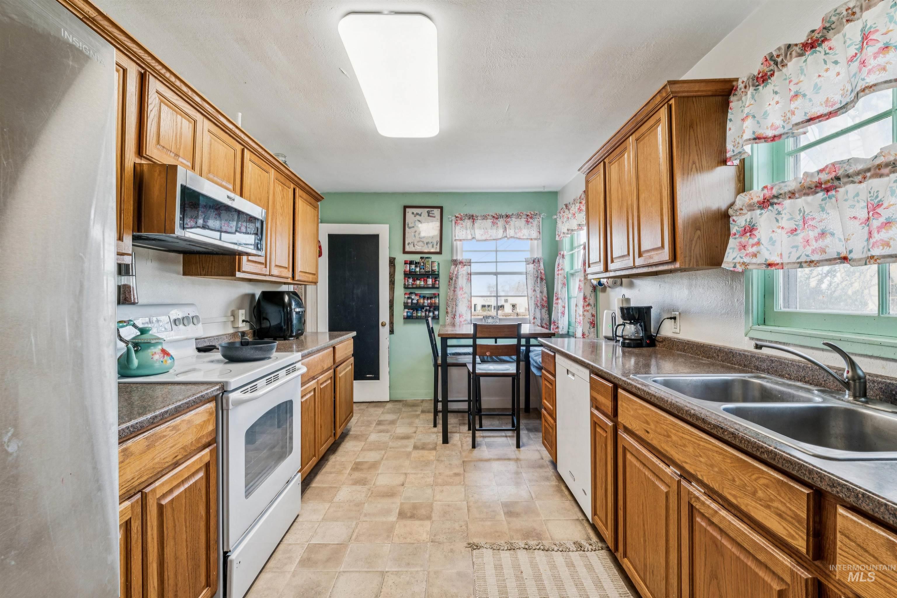 124 Halstead Street Caldwell, ID 83605 - Photo 16 of 42 Kitchen with stainless steel appliances, dark countertops, wood finish cabinets, and stone finish flooring