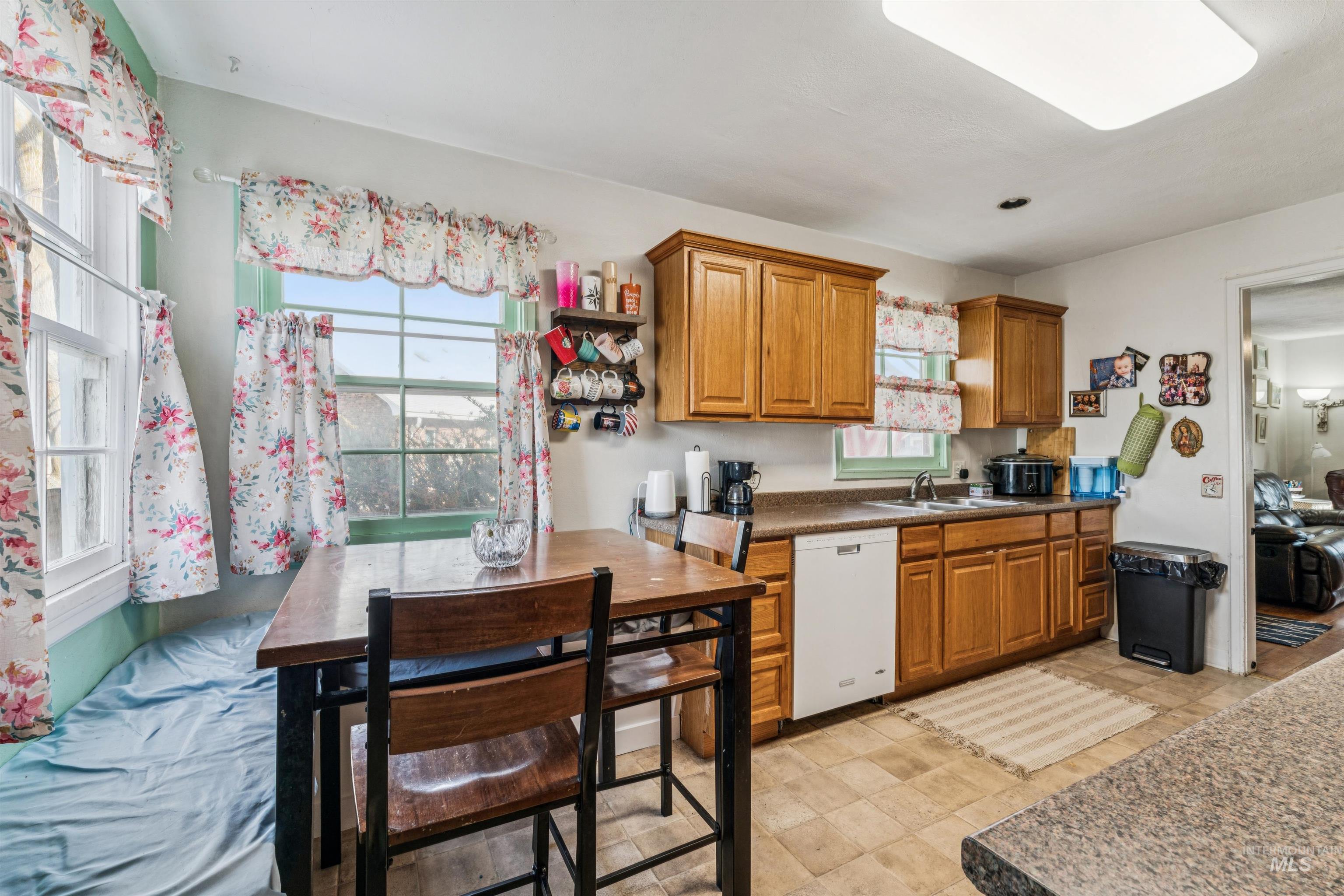 124 Halstead Street Caldwell, ID 83605 - Photo 18 of 42 Kitchen with wood finish cabinetry, white dishwasher, dark countertops, and stone finish flooring